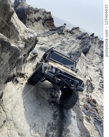 A radio-controlled SUV driving through the rocky terrain of nature A radio-controlled SUV driving through the rocky terrain of nature 125404937