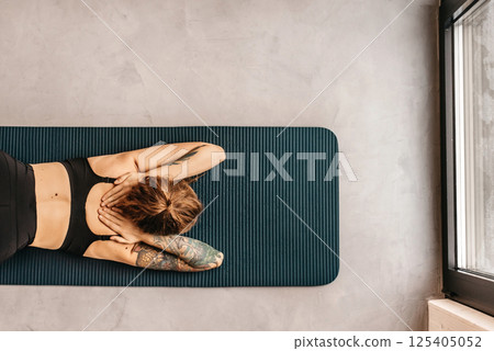 Woman Practicing Yoga in Puppy Pose Variation Woman Practicing Yoga in Puppy Pose Variation 125405052