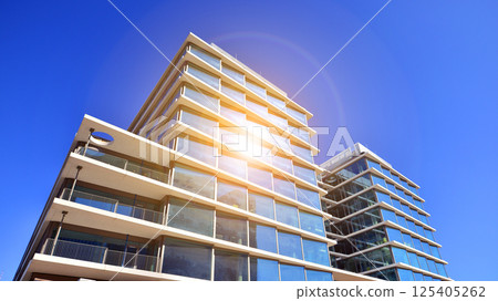 Downtown corporate business district architecture. Glass reflective office buildings against blue sky and sun light. Economy, finances, business activity concept. Rising sun on the horizon. 125405262