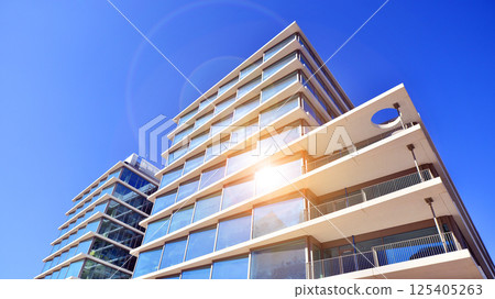 Downtown corporate business district architecture. Glass reflective office buildings against blue sky and sun light. Economy, finances, business activity concept. Rising sun on the horizon. 125405263