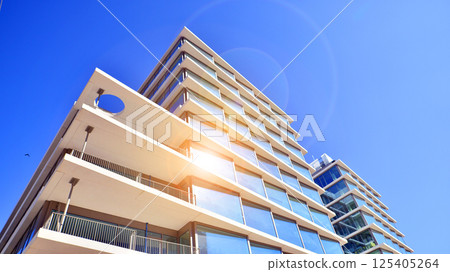 Downtown corporate business district architecture. Glass reflective office buildings against blue sky and sun light. Economy, finances, business activity concept. Rising sun on the horizon. 125405264