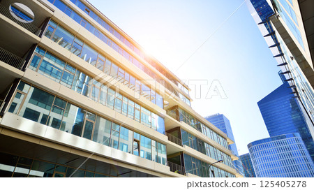 Downtown corporate business district architecture. Glass reflective office buildings against blue sky and sun light. Economy, finances, business activity concept. Rising sun on the horizon. Downtown corporate business district architecture. Glass reflective office buildings against blue sky and sun light. Economy, finances, business activity concept. Rising sun on the horizon. 125405278
