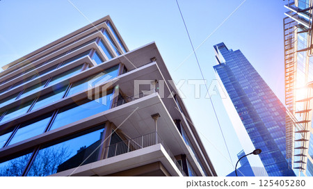 Downtown corporate business district architecture. Glass reflective office buildings against blue sky and sun light. Economy, finances, business activity concept. Rising sun on the horizon. Downtown corporate business district architecture. Glass reflective office buildings against blue sky and sun light. Economy, finances, business activity concept. Rising sun on the horizon. 125405280