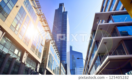 Downtown corporate business district architecture. Glass reflective office buildings against blue sky and sun light. Economy, finances, business activity concept. Rising sun on the horizon. 125405282