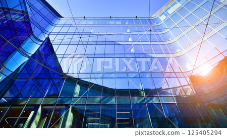 Downtown corporate business district architecture. Glass reflective office buildings against blue sky and sun light. Economy, finances, business activity concept. Rising sun on the horizon. 125405294