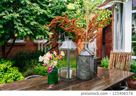 wooden table with lanterns and dried flowers. The yard in the house. 125406578