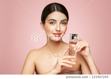 Smiling woman holds bottle with cosmetic tonic 125407204
