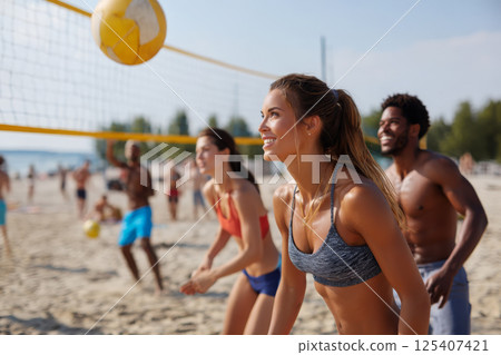 Young and athletic people playing volleyball on the beach 125407421