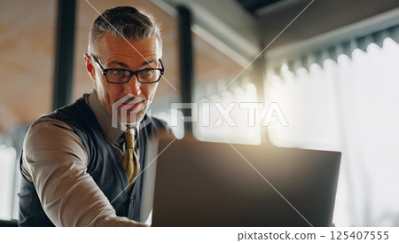 A Focused and Dedicated Professional Working on a Laptop in a Modern Office Environment 125407555