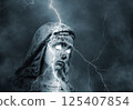 Statue of the sacred virgin Mary with glowing eyes struck by lightning in a stormy sky 125407854