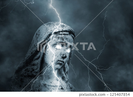 Statue of the sacred virgin Mary with glowing eyes struck by lightning in a stormy sky 125407854