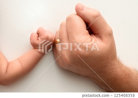 Two hands: man and child. Father and son touching fists. Dad and newborn son boys holding hands together. Little and big fists of father and son.  Two hands: man and child. Father and son touching fists. Dad and newborn son boys holding hands together. Little and big fists of father and son.  125408358
