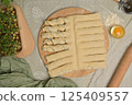 Top view twisted dough strips on wooden board. Cutter, egg, green towel, microgreens sprouts on kitchen table. Home cooking baking puffs 125409557