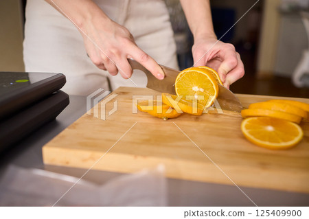 Slicing Fresh Oranges on a Beautiful Wooden Cutting Board to Enhance Your Culinary Skills 125409900
