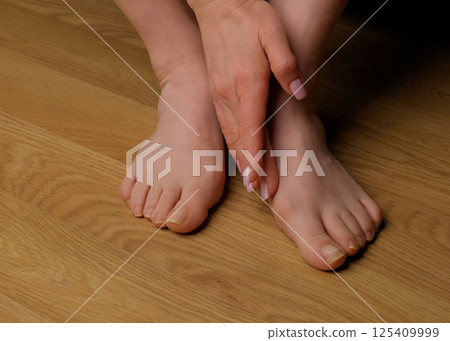 Close-up of a woman s foot with hallux valgus bunion and signs of toenail fungus. Her hand gently touches the deformed big toe, illustrating common foot problems and the need for medical care. Close-up of a woman s foot with hallux valgus bunion and signs of toenail fungus. Her hand gently touches the deformed big toe, illustrating common foot problems and the need for medical care. 125409999