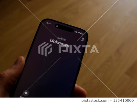 Fraud or fraudulent schemes. Close-up of a male hand holding a phone with an unexpected incoming call from an unknown Fraud or fraudulent schemes. Close-up of a male hand holding a phone with an unexpected incoming call from an unknown 125410000
