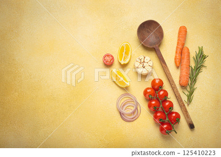 Cooking ingredients, fresh vegetables and wooden spoon on yellow background with copy space, cooking background Cooking ingredients, fresh vegetables and wooden spoon on yellow background with copy space, cooking background 125410223