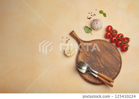 Food background with wooden cutting board, tomatoes, garlic, fresh basil and spices on light beige table, space for text Food background with wooden cutting board, tomatoes, garlic, fresh basil and spices on light beige table, space for text 125410224