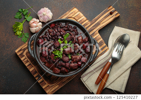 Brazilian feijoada with black beans, sausage, and meat in a pot, top view 125410227