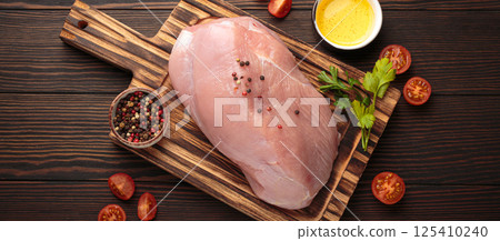 Raw healthy turkey fillet with herbs and spices on wooden cutting board top view 125410240