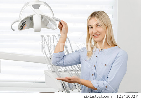 Dentist adjusting dental light in clinic 125410327