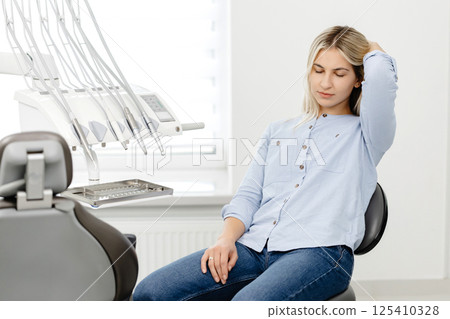 Young woman feeling relaxed sitting on dentist chair waiting for her dental checkup Young woman feeling relaxed sitting on dentist chair waiting for her dental checkup 125410328