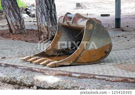 Detached bucket of the escort lying on the ground Detached bucket of the escort lying on the ground 125410393