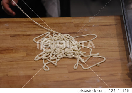 The chef makes noodles by hand. Handmade noodles for lagman. The chef makes noodles by hand. Handmade noodles for lagman. 125411116