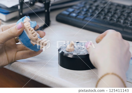 Dental technician skillfully fabricates dentures using jaw models 125411143