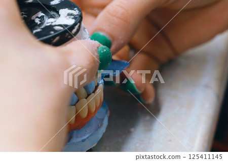 Dental technician evaluates denture model for proper bite alignment 125411145