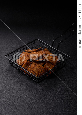 Crispy homemade brown bread chips with seeds and grains, salt, spices 125411203