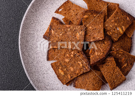 Crispy homemade brown bread chips with seeds and grains, salt, spices 125411219