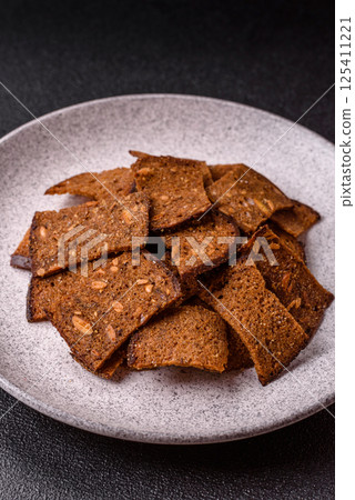 Crispy homemade brown bread chips with seeds and grains, salt, spices 125411221