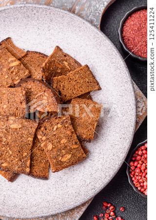 Crispy homemade brown bread chips with seeds and grains, salt, spices 125411224