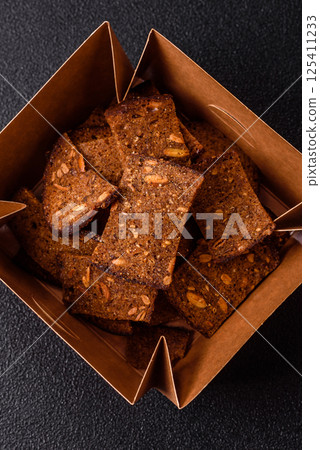 Crispy homemade brown bread chips with seeds and grains, salt, spices 125411233