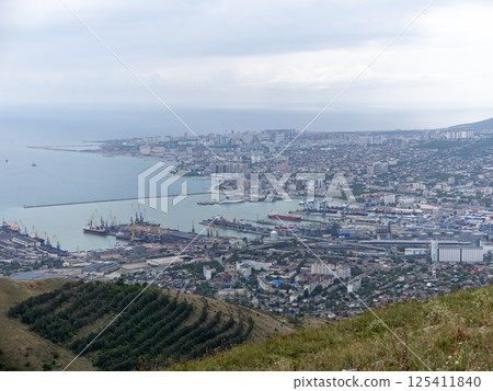 Panoramic view of Novorossiysk City and Tsemess Bay at sunrise. Morning cityscape of large port at Black Sea coast in Russia 125411840