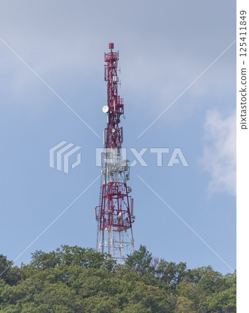 Directional antenna array on a red and white communication tower against sky Directional antenna array on a red and white communication tower against sky 125411849