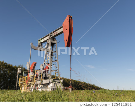 Operating oil and gas well in oil field, profiled against the blue sky 125411891
