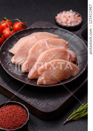Raw chicken or turkey fillet cut into slices with salt, spices and herbs Raw chicken or turkey fillet cut into slices with salt, spices and herbs 125411967