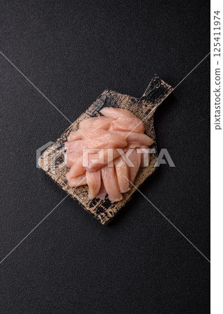 Raw chicken or turkey fillet cut into slices with salt, spices and herbs 125411974