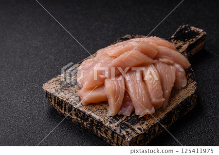 Raw chicken or turkey fillet cut into slices with salt, spices and herbs Raw chicken or turkey fillet cut into slices with salt, spices and herbs 125411975