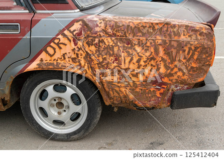 Rusty abandoned drift car showing signs of damage and wear Rusty abandoned drift car showing signs of damage and wear 125412404