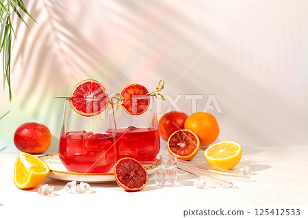 Royal cocktail of blood orange, ice cubes, rum and tequila. Summer party and restaurant relaxation concept. Banner with glasses of alcoholic drinks and tropical fruits. Menu for a bar or cafe 125412533