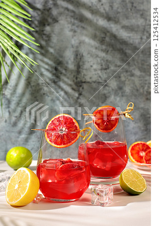 Royal cocktail of blood orange, ice cubes, rum and tequila. Summer party and restaurant relaxation concept. Banner with glasses of alcoholic drinks and tropical fruits. Menu for a bar or cafe 125412534