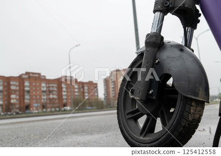 Electric scooter wheel standing on wet asphalt road after rain in city Electric scooter wheel standing on wet asphalt road after rain in city 125412558