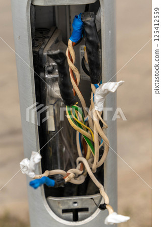 Electrical junction box showing exposed and damaged wiring requiring repair 125412559
