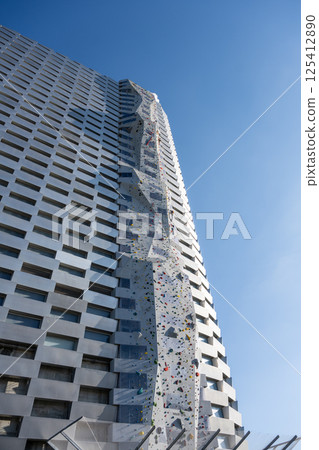 Climbers tackle the tallest climbing wall in the world located at Amager Bakke, an iconic waste-to-energy facility in Copenhagen, Denmark, under a clear blue sky. Climbers tackle the tallest climbing wall in the world located at Amager Bakke, an iconic waste-to-energy facility in Copenhagen, Denmark, under a clear blue sky. 125412890