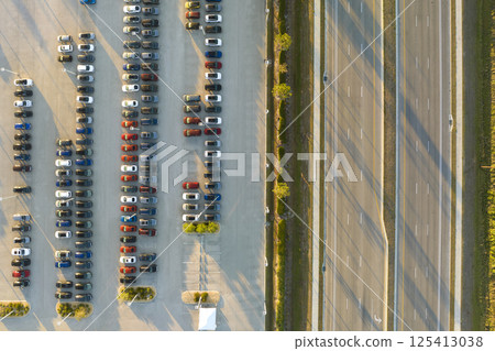 Large parking lot of local dealer with many brand new cars parked for sale on highway roadside. Development of american automotive industry and distribution of manufactured vehicles concept 125413038