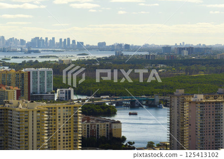 High angle view of Sunny Isles Beach city with expensive highrise hotels and condo buildings on Atlantic ocean shore. American tourism infrastructure in coastal southern Florida High angle view of Sunny Isles Beach city with expensive highrise hotels and condo buildings on Atlantic ocean shore. American tourism infrastructure in coastal southern Florida 125413102