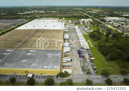 High angle view of big commercial shipping center with many freight trucks unloading and uploading goods for further distribution. Global economy concept High angle view of big commercial shipping center with many freight trucks unloading and uploading goods for further distribution. Global economy concept 125413103